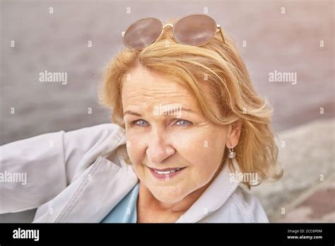 Attractive senior active caucasian woman about 62 years old with blond hair and sunglasses has a ...