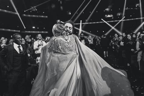 a man in a suit and tie hugging a woman on the dance floor at a wedding