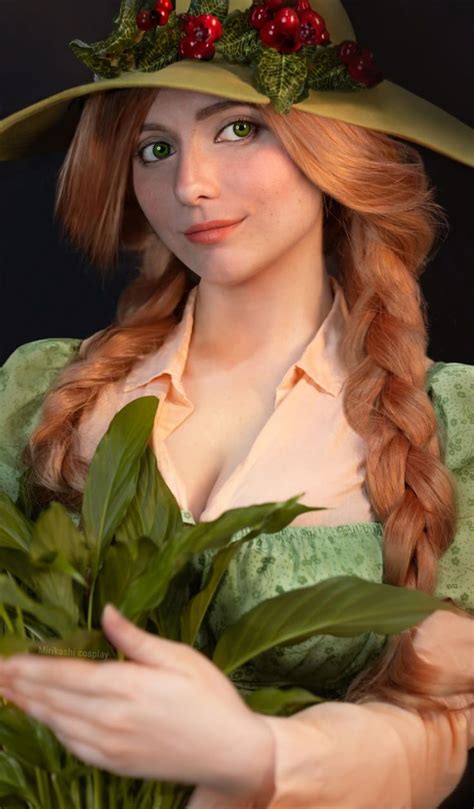 a woman in a green dress and hat holding some leaves while wearing a ...