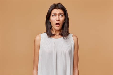 Retrato de mujer asustada en pánico nervioso asustado vestido con vestido blanco, boca abierta ...