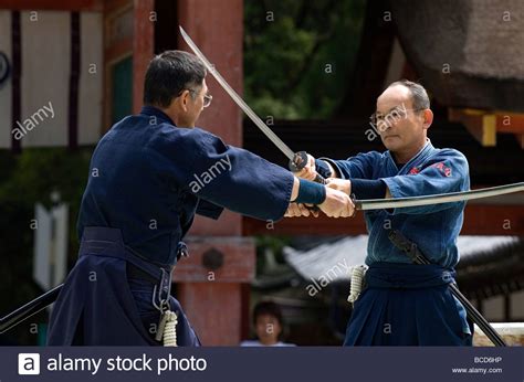 Two men engaged in a sword fight using real samurai swords during a martial arts demonstration ...