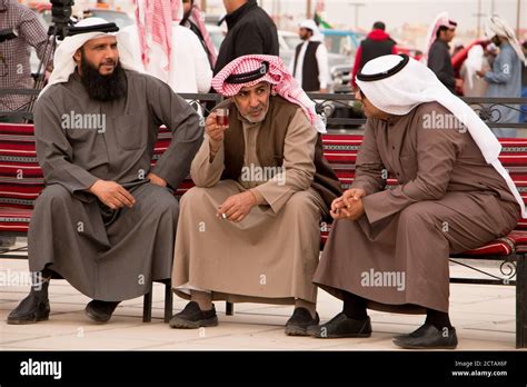 Three Kuwaiti men talking and smoking on a bench. Dressed in ...