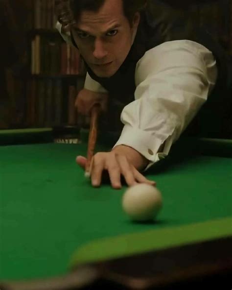 a man leaning over a pool table with a cue in his hand and one eye on the ball