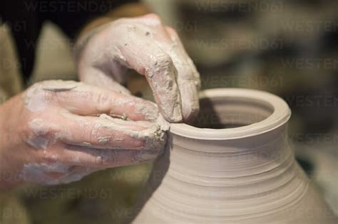 Close up of male potter's hands shaping clay pot on pottery wheel in workshop stock photo