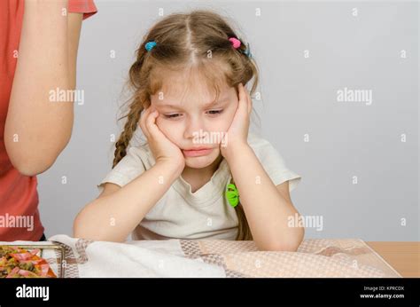 The baby girl with a sad expression on her face sitting at the kitchen table Stock Photo - Alamy