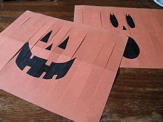 two pieces of paper cut out to look like jack o'lantern faces on a table