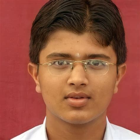 a young man wearing glasses in front of a red wall with a white shirt and tie