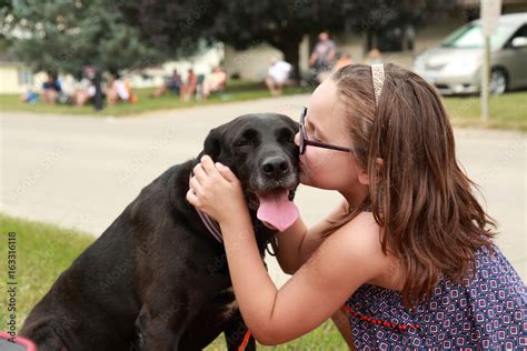 A young Caucasian girl kissing a black dog with white spots Stock Photo ...