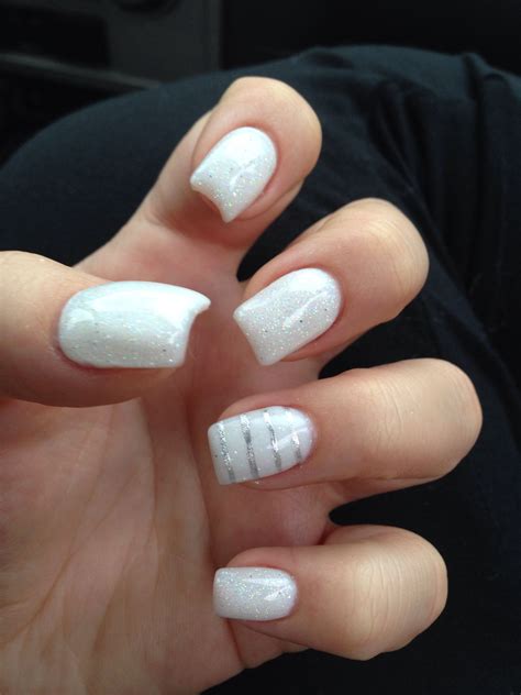 a woman's hand with white and silver nail polishes on her nails,