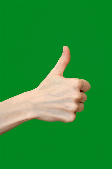 A hand giving a thumbs up sign against a green background photo – Free ...