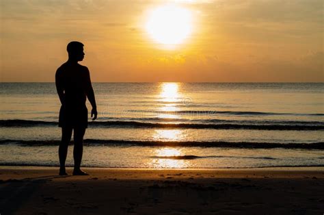 The Silhouette Photo of a Man Standing Alone on the Beach Enjoy Sunrise ...