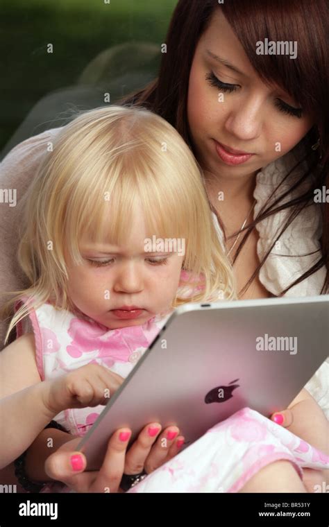 Mother and her two year old daughter using an Apple iPad in their home ...