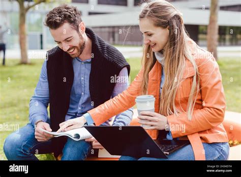 Fellow students looking into a book on college campus Stock Photo - Alamy