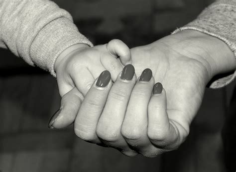 black and white photograph of two people holding each other's hands with their fingers