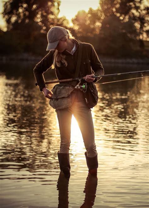 a woman standing in the water while fishing