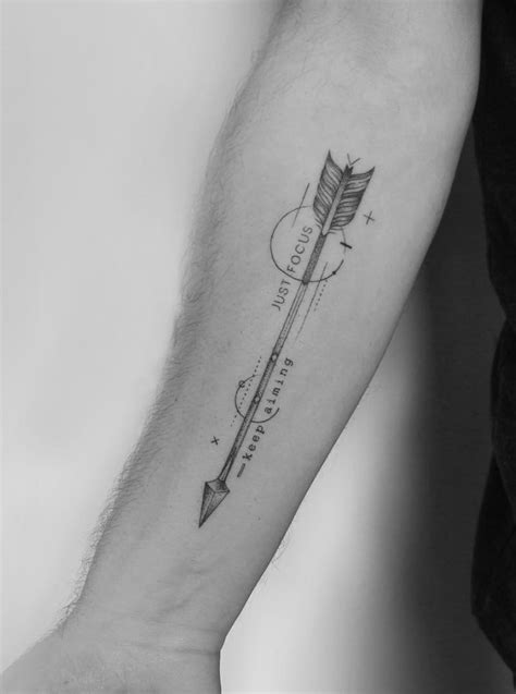 a black and white photo of a person's arm with an arrow tattoo on it