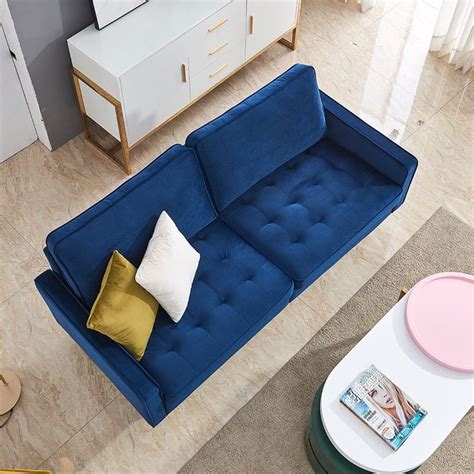 a blue couch sitting on top of a living room floor next to a white table