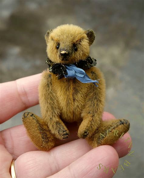 a small brown teddy bear sitting on top of a persons hand