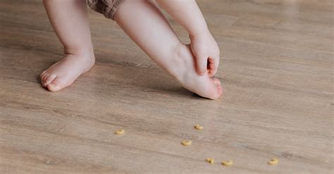 Anonymous toddler trying to remove stuck pasta from foot while ...