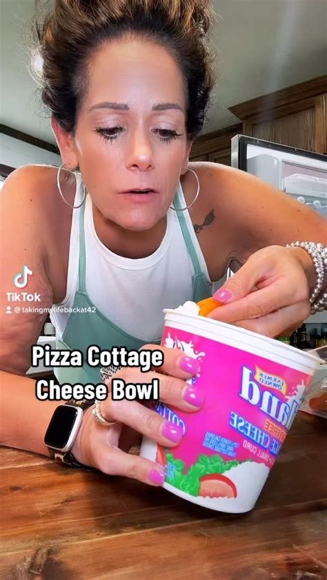 a woman eating pizza cottage cheese bowl from a container with her hands on the counter