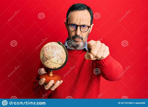 Middle Age Hispanic Man Holding Vintage World Ball Pointing with Finger To the Camera and To You ...