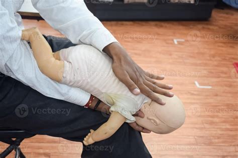 Man performing CPR on baby training doll dummy with one hand compression. First Aid Training ...