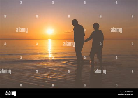 Senior couple walking at sunset Stock Photo - Alamy