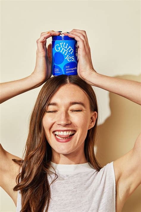 a smiling woman holding up a can of pure blue water to her head with ...