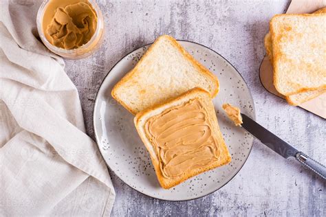 Peanut butter sandwich on toasted bread on a plate and jar of butter on the table. Top view ...