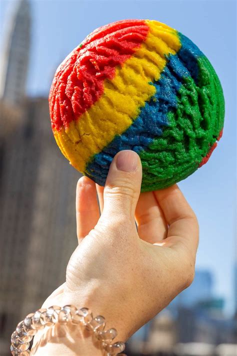 Hand holding a rainbow cookie in red, yellow, blue and green, against the background of the ...