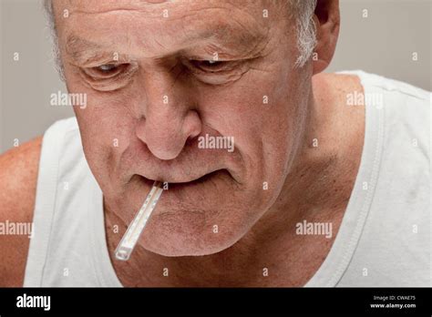 Senior man with thermometer in mouth Stock Photo - Alamy