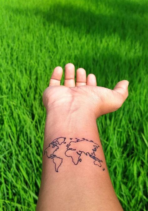 a person's arm with a small world map tattoo on it, in the grass