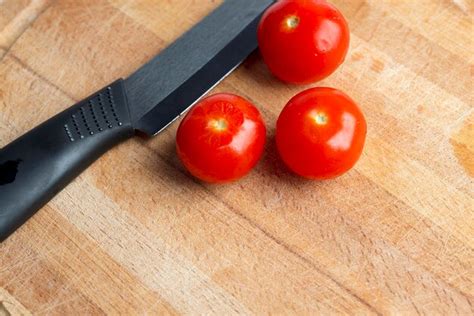 Premium Photo | Black ceramic knife on a wooden board with cherry tomatoes