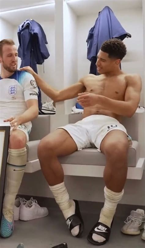 two men sitting next to each other in a locker room with soccer gear on the wall