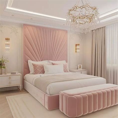 a bedroom with a large bed, chandelier and pink velvet upholstered headboard