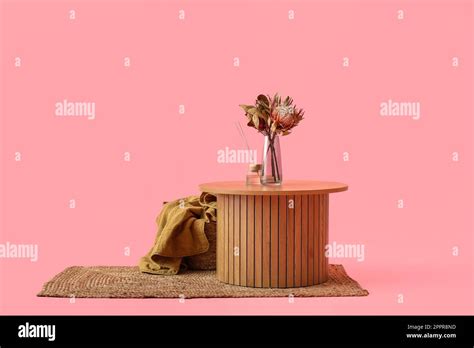 Wooden coffee table with dried flowers in vase and reed diffusers on pink background Stock Photo ...