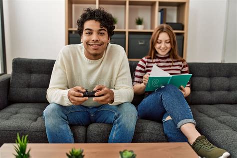 Man Playing Video Game while Girlfriend Reading Book at Home Stock Image - Image of joystick ...