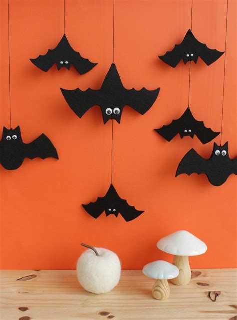 a group of bats hanging from strings next to an apple and mushrooms on a table