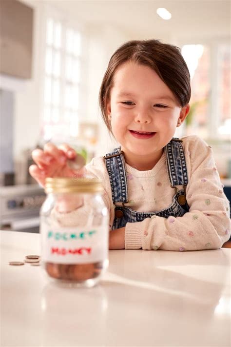 Girl Saving Money into Jar Labelled Pocket Money on Kitchen Counter at Home Stock Image - Image ...