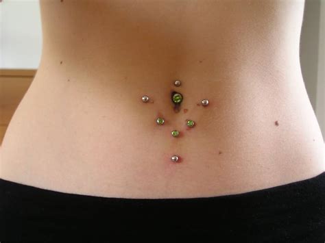 Surface Navel Piercing With Green And Silver Studs