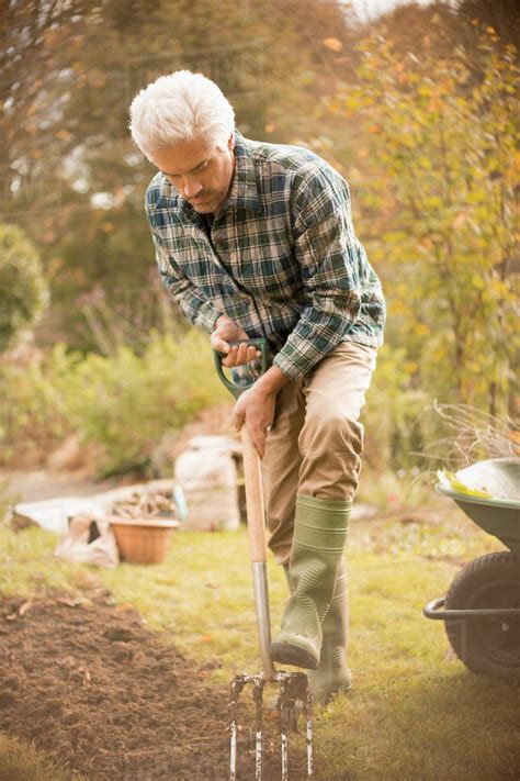 Man gardening digging dirt in autumn garden - Stock Photo - Dissolve