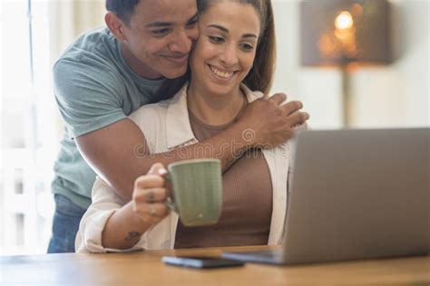 Young Interracial Couple Live Together at Home and Smile Looking a Laptop on the Table. Boy ...