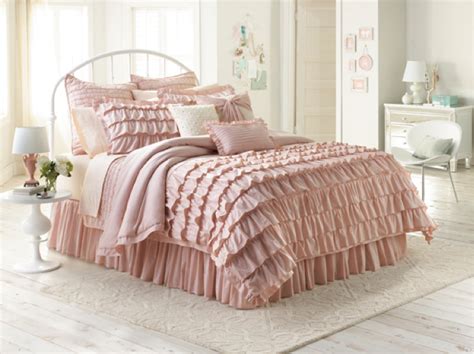 a bed with pink ruffled sheets and pillows