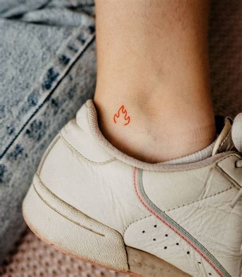 Minimalist red flame tattoo on the ankle.