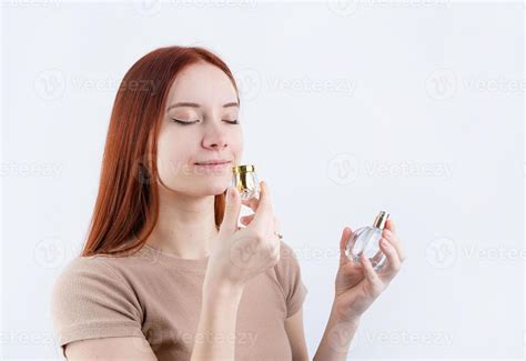 Happy young woman smelling perfume, holding glass bottle isolated on ...