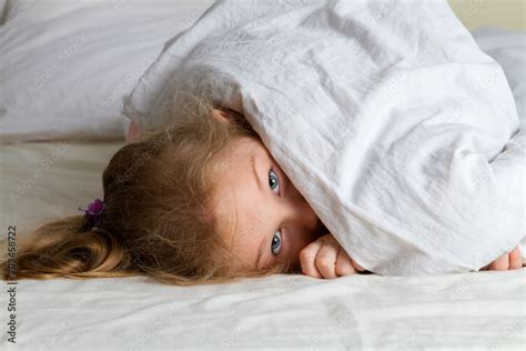 little girl lying under blanket Stock Photo | Adobe Stock