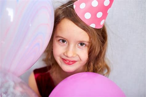 Premium Photo | Joyful little girl in pink dress and hat play with balloons at birthday party