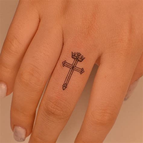 Cross and crown tattoo located on the finger.