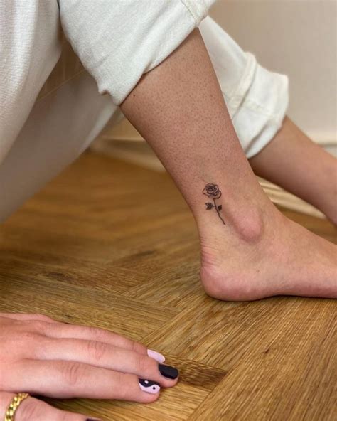 Rose tattoo located on the ankle, illustrative style.