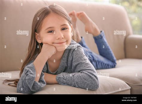 Cute little girl lying on sofa at home Stock Photo - Alamy